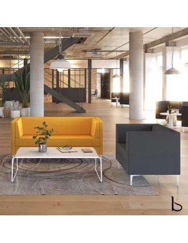 Deux fauteuils d’accueil, l’un jaune et l’autre gris, autour d’une table basse blanche dans un espace réception lumineux.